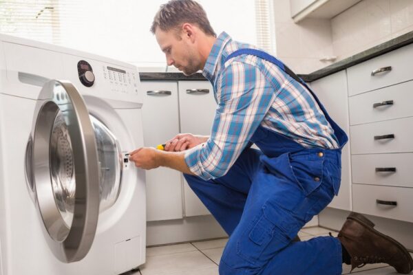 Handyman fixing a washing machine in the kitchen